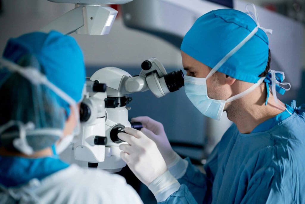 Surgeons performing an eye surgery under the microscope at the hospital - healthcare and medicine concepts