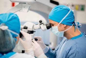 Surgeon performing an eye surgery under the microscope - healthcare and medicine concepts