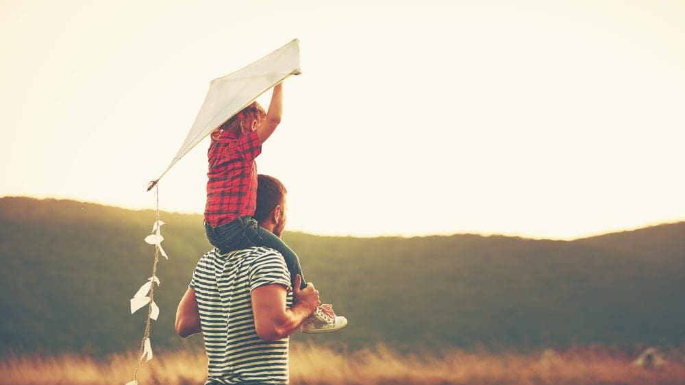 man and daughter holding kite