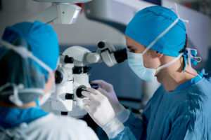 chirurgen die een oogoperatie onder de microscoop in het ziekenhuis uitvoeren - healthcare and medicine concepts