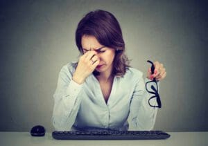 Femme à lunettes souffrant de fatigue oculaire après de longues heures de travail sur ordinateur