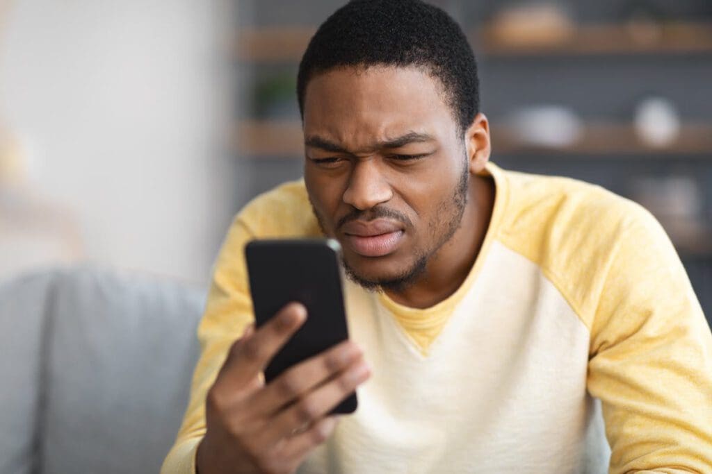 man squinting to see phone