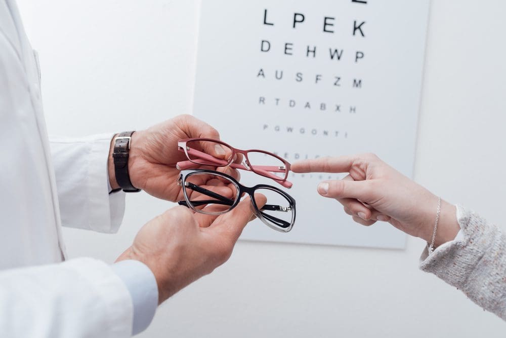 woman receiving glasses in front of eye exam