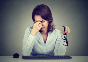 Woman with glasses suffering from eyestrain after long hours working on computer
