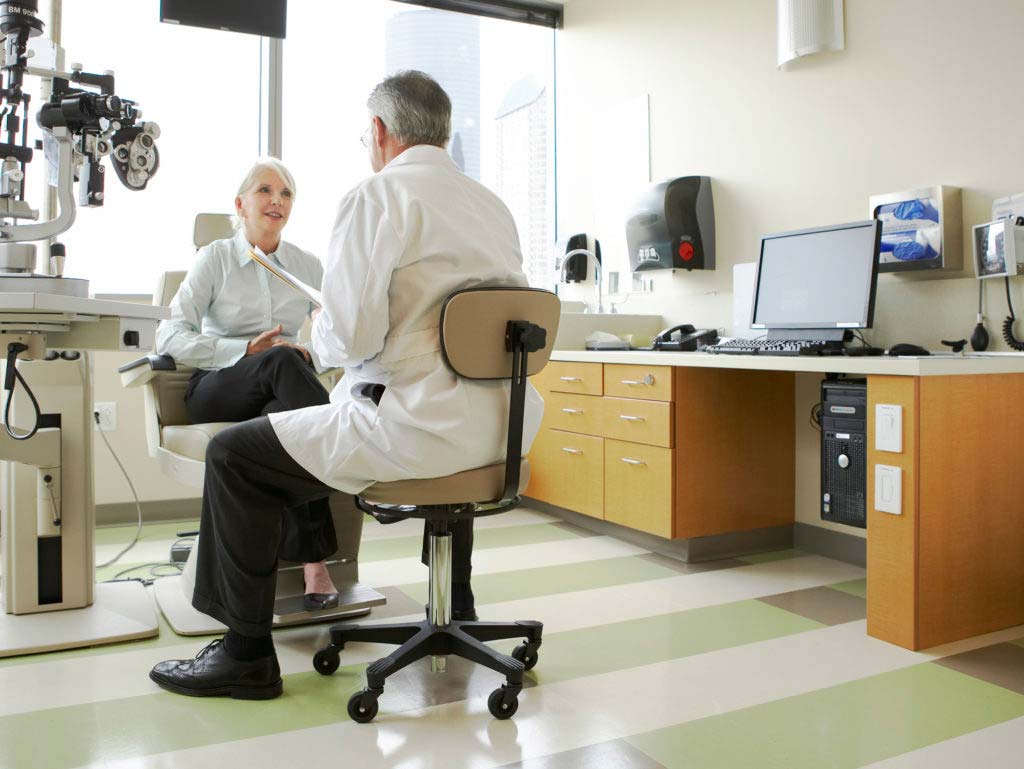 An opthamologist is listening to the patient in an exam room.